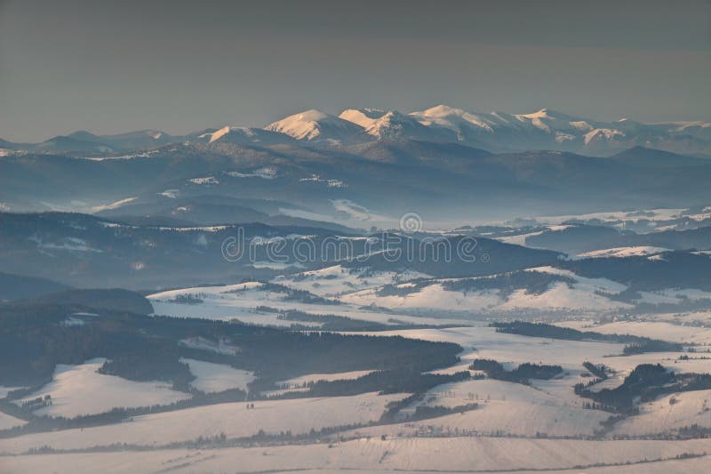 Snowy Little Fatra peaks and forest in mist at sunrise Slovakia