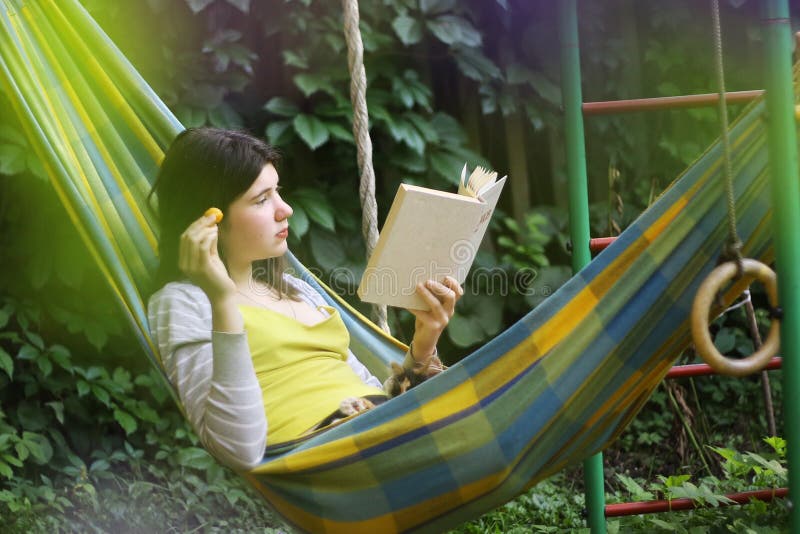 Ruhige Szene mit jugendlich Mädchen in der Hängematte mit Aprikosenlesebuch lizenzfreie stockfotografie Ruhige Szene mit jugendlich Mädchen in der Hängematte mit Aprikosenlesebuch lizenzfreie stockfotografie