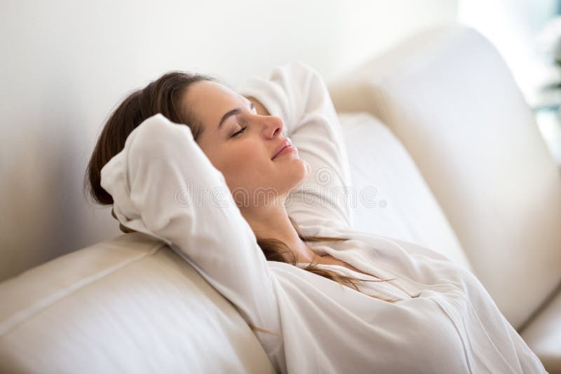 Ruhige tausendjährige Frau, die auf bequemes Sofa Atmungsfre sich entspannt