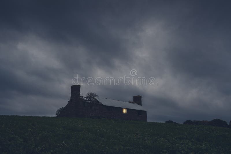 A ruined house in the middle of the countryside. With a light shining from a broken window on a stormy night