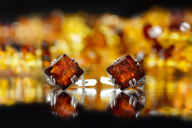 Ruit van close-up de zilveren oorringen met authentieke natuurlijke Baltische amber op zwarte oppervlakte stock afbeeldingen Ruit van close-up de zilveren oorringen met authentieke natuurlijke Baltische amber op zwarte oppervlakte stock afbeeldingen