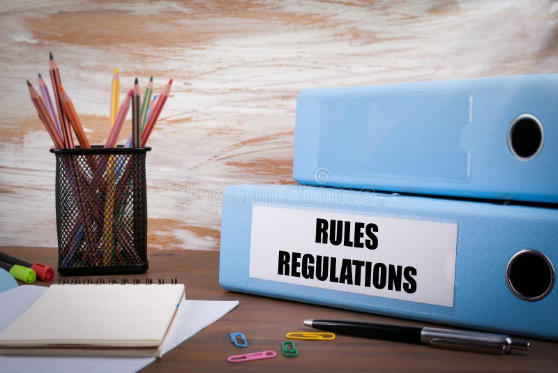 Rules And Regulations, Office Binder on Wooden Desk. On the table colored pencils, pen, notebook paper