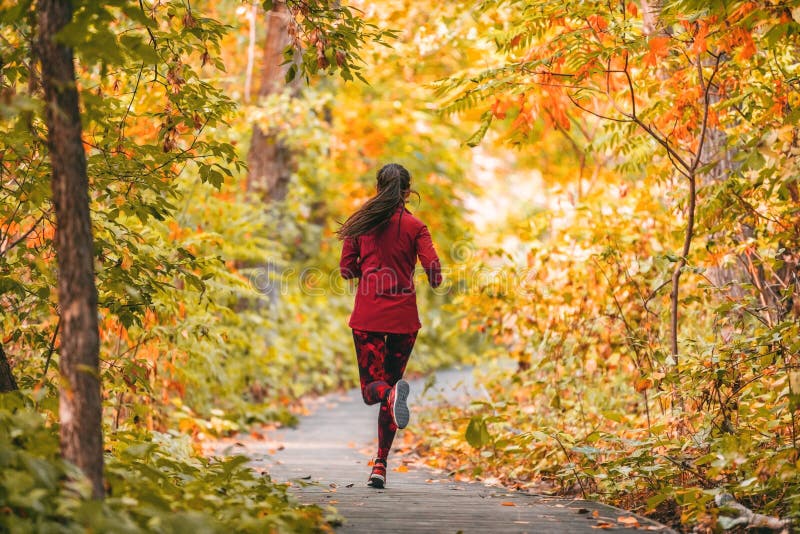 Run woman jogging in outdoor fall autumn foliage nature background in forest. Trail running runner athlete training. Cardio outdoors, orange colors tree leaves