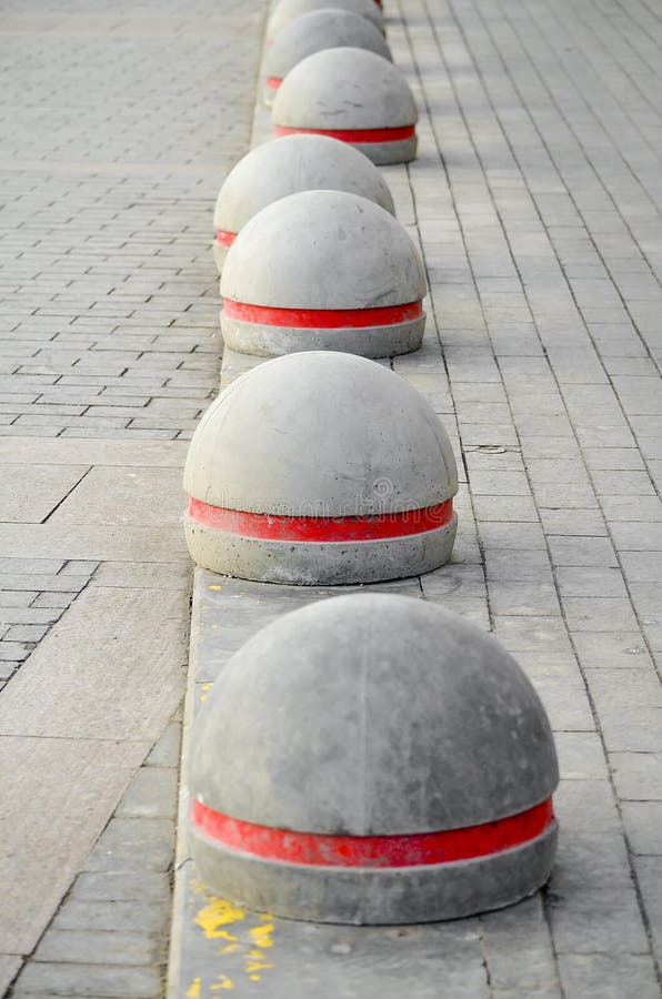 Round stone columns with a red strip standing in a row on a stone blocks. Round stone columns with a red strip standing in a row on a stone blocks.