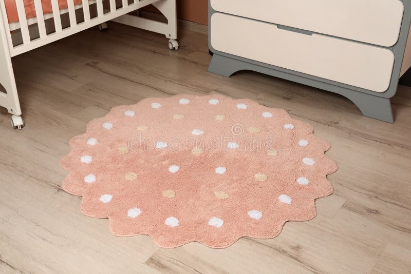 Runder rosa Teppich mit Polka-Punkt-Muster auf dem Boden in Babyzimmer stockfotografie