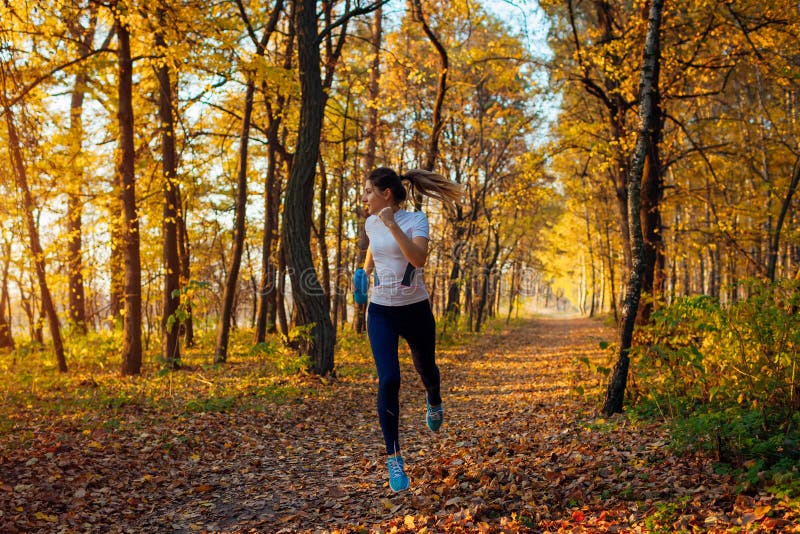 Runner Exercising in Autumn Park. Woman Running with Water Bottle at ...