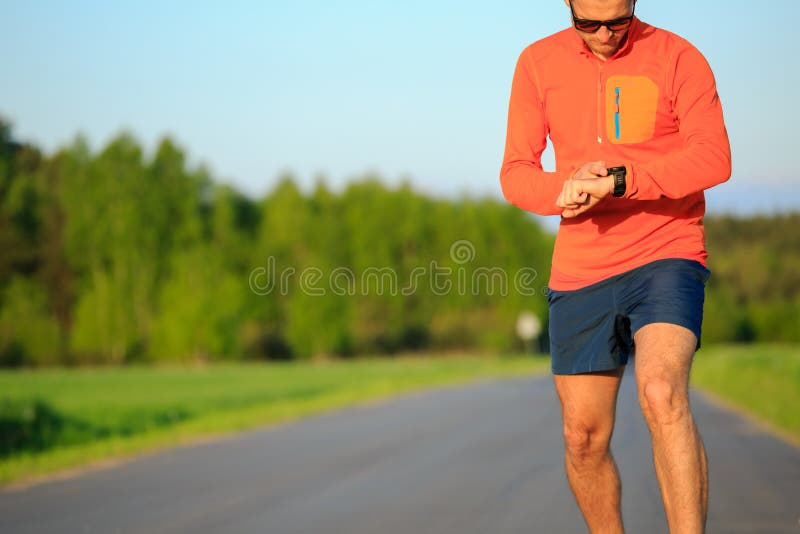 Runner training and checking stopwatch smart watch, cross country running checking performance activity monitor tracker, GPS position or heart rate pulse. Sport smartwatch, inspiration and accomplish motivation.