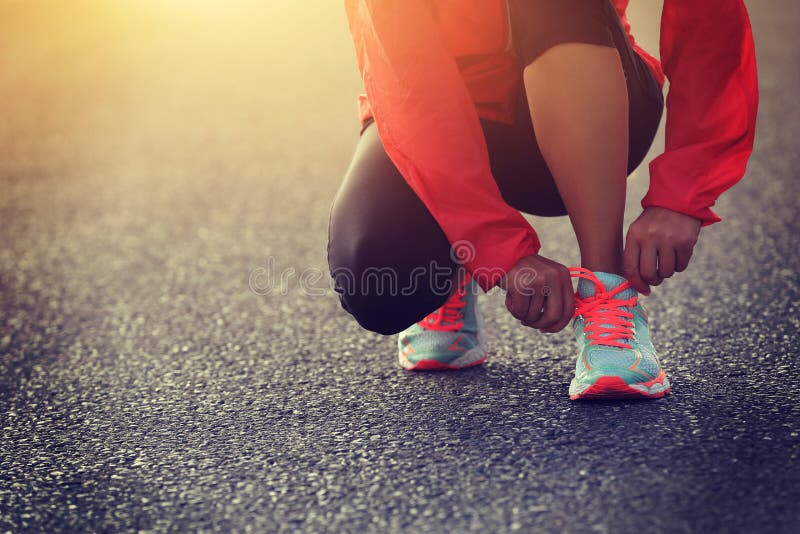 Runner tying shoelace on country road