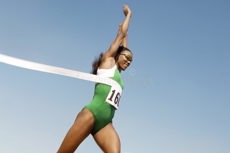 Side view of a female runner winning race against the blue sky