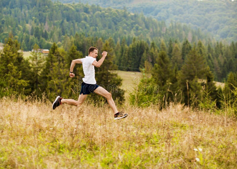 Running fitness man sprinting outdoors with beautiful mountains landscape on background. Caucasian sport male runner training for