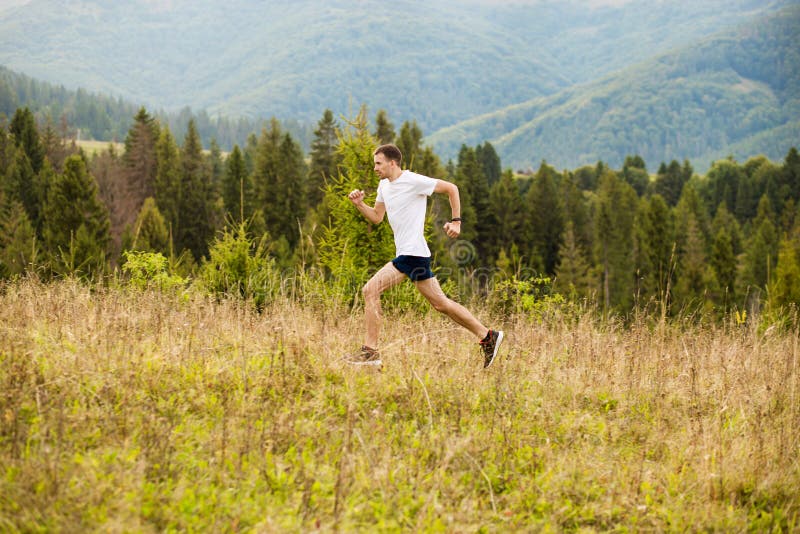 Running fitness man sprinting outdoors with beautiful mountains landscape on background. Caucasian sport male runner training for