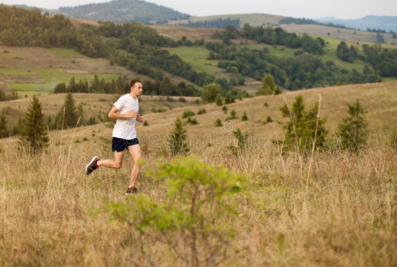 Running fitness man sprinting outdoors with beautiful mountains landscape on background. Caucasian sport male runner training for