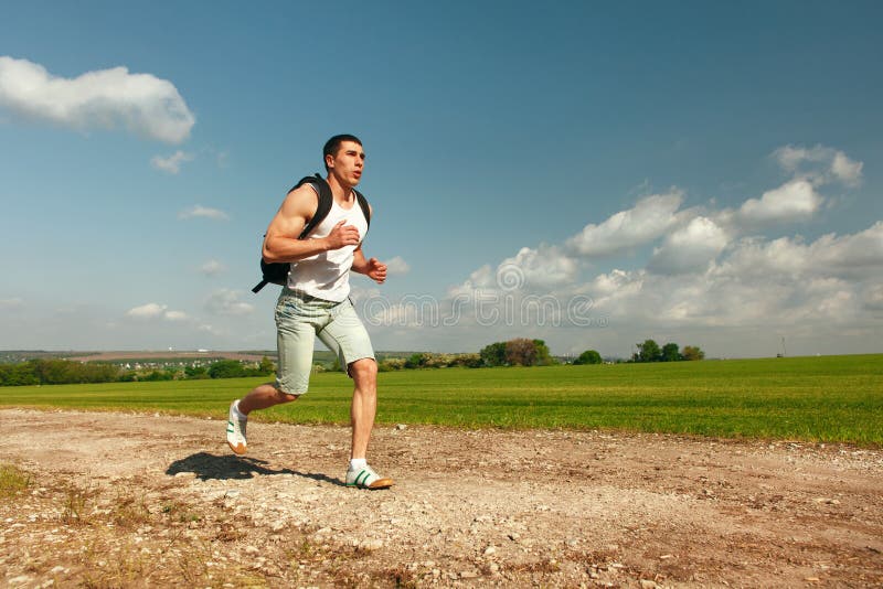 Running man sprinting cross on a trail. Male fit sport fitness model training for marathon outside in beautiful landscape