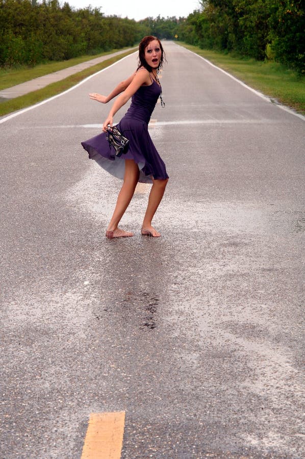 Una spaventato, sorpreso ragazza correre su una deserta strada sotto la pioggia.