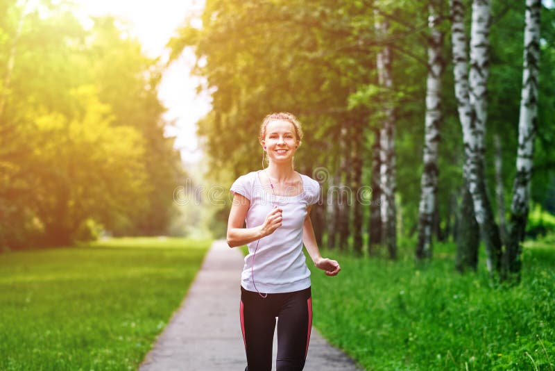 Running woman atletic spotsman trains in the summer park. Outdoor fitness portrait after rain