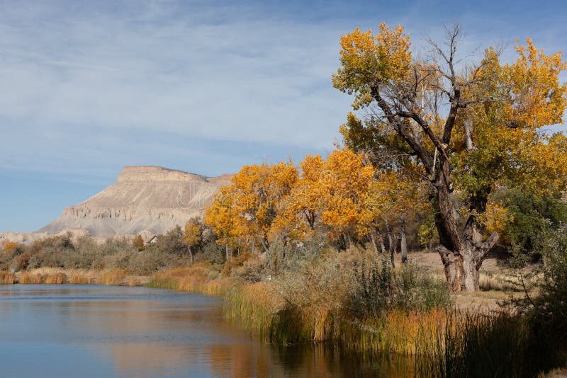 Rural pond with distant mountains in Autumn. Pond with Mt. Garfield in the distance. Autumn cottonwoods on the shore stock image Rural pond with distant mountains in Autumn. Pond with Mt. Garfield in the distance. Autumn cottonwoods on the shore stock image