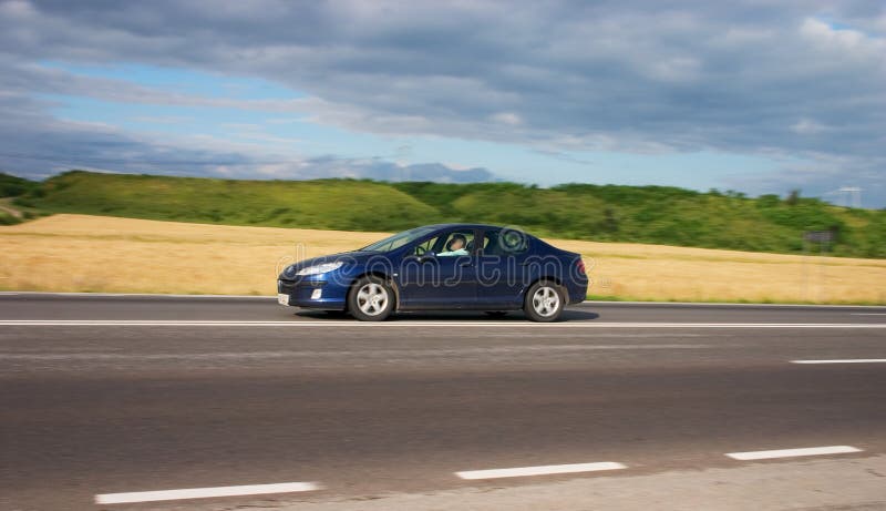 Blue car speeding down the highway with blurry background. Blue car speeding down the highway with blurry background