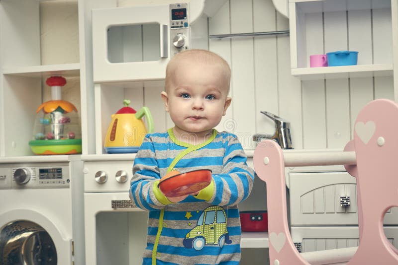 Rusland St Petersburg 19 maart, 2019 Een kleine kindspelen in de keuken van de kinderen één éénjarigejongen met genoegen stock foto Rusland St Petersburg 19 maart, 2019 Een kleine kindspelen in de keuken van de kinderen één éénjarigejongen met genoegen stock foto