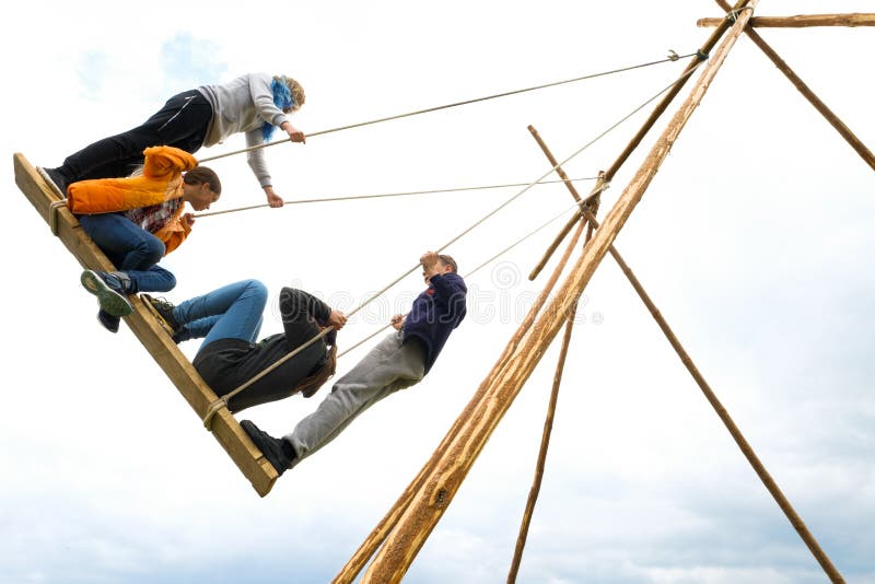 Rusland, Tyumen, 15 06 2019 Kinderen van verschillende leeftijden en schommeling op de grote ouderwetse houten schommeling, tegen stock foto's Rusland, Tyumen, 15 06 2019 Kinderen van verschillende leeftijden en schommeling op de grote ouderwetse houten schommeling, tegen stock foto's