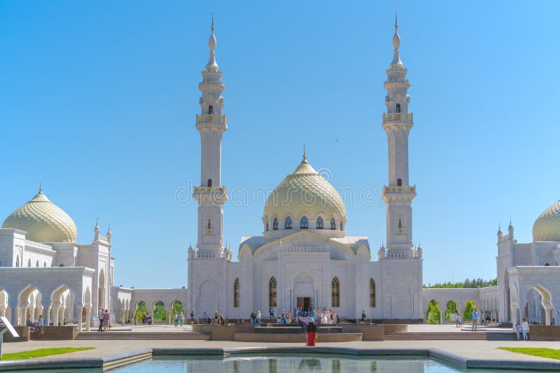 Russia, Bolgar - June 08, 2019. White mosque close up. People look at the mosque, a woman in a red dress and scarf. Lake near the royalty free stock photography Russia, Bolgar - June 08, 2019. White mosque close up. People look at the mosque, a woman in a red dress and scarf. Lake near the royalty free stock photography