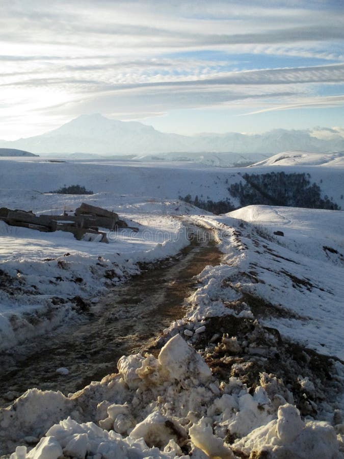 Russia, Caucasia. Road and snow on mountain and blue sky background, vertical view.