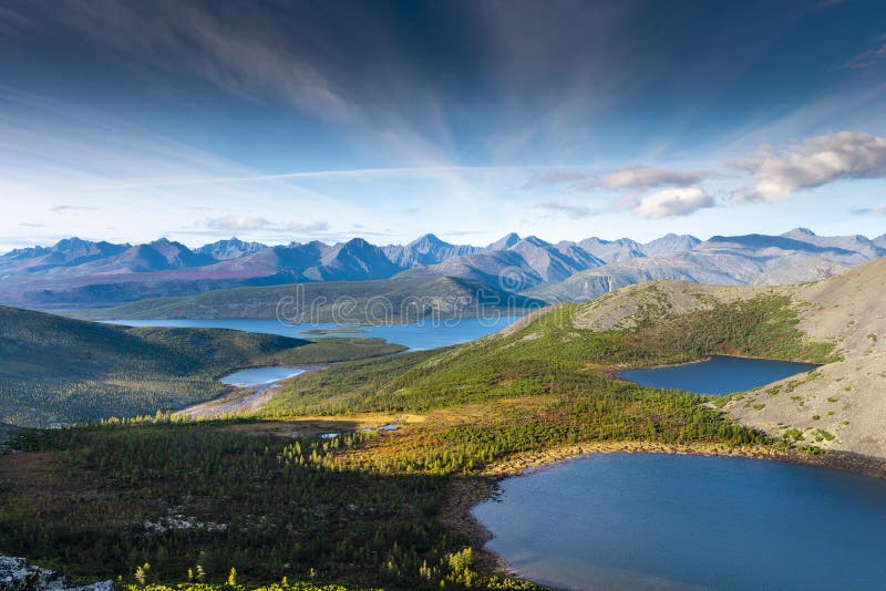 Russia. Magadan Region. A beautiful forest lake against the backdrop of the Big Anngachak mountain range. Autumn in the vicinity