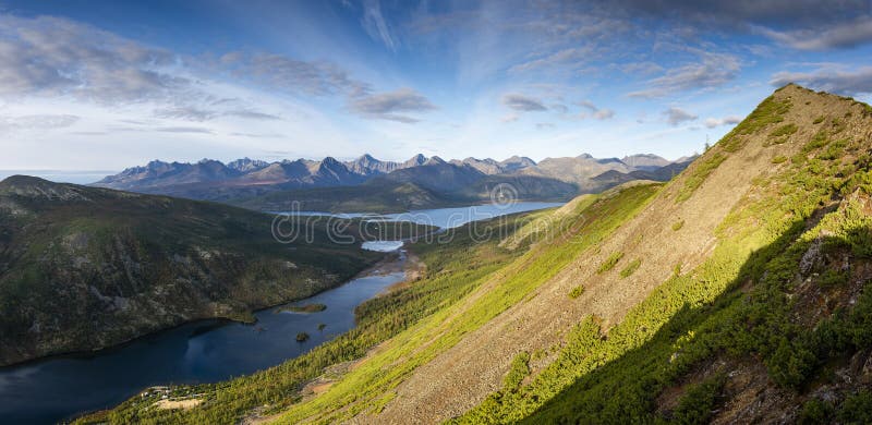 Russia. Magadan Region. A beautiful forest lake against the backdrop of the Big Anngachak mountain range. Autumn in the vicinity