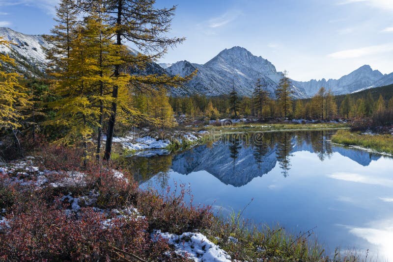 Russia. Magadan Region. A beautiful forest lake against the backdrop of the Big Anngachak mountain range. Autumn in the vicinity