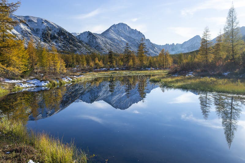 Russia. Magadan Region. A beautiful forest lake against the backdrop of the Big Anngachak mountain range. Autumn in the vicinity