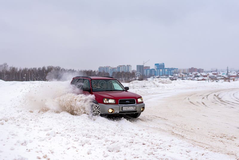 Russia, Novosibirsk-January 7, 2020. Japanese car red `Subaru Forester` rides in the drift sideways raising snow