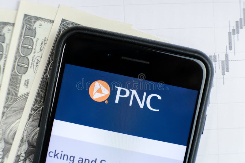 RUSSIA, ST.PETERSBURG, April 4, 2019: site with Logo of the bank PNC Financial Services in the smartphone lying on paper with charts and one hundred dollar bills. RUSSIA, ST.PETERSBURG, April 4, 2019: site with Logo of the bank PNC Financial Services in the smartphone lying on paper with charts and one hundred dollar bills
