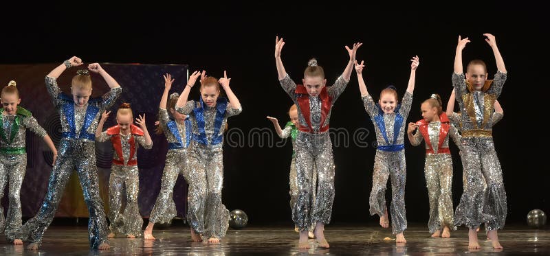 Performance of a children`s dance group in shiny costumes, in the style of disco at the open festival of creativity