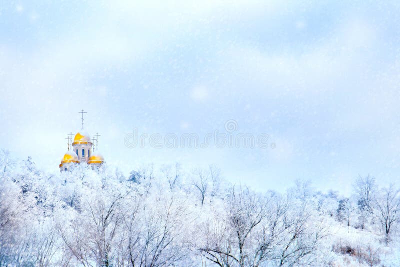 Russian winter landscape. Golden domes of the church against the background of a winter white forest. Snowing.