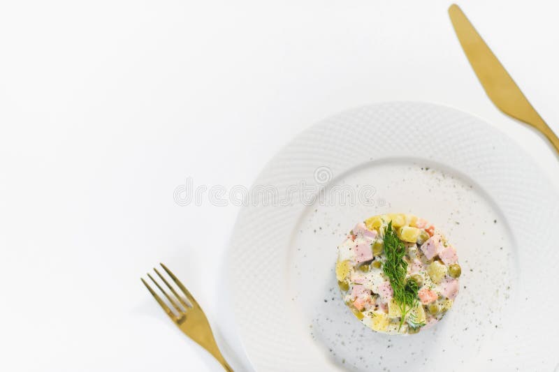 Russische salade op een witte plaat met een Gouden mes en vork op een witte achtergrond royalty-vrije stock foto's Russische salade op een witte plaat met een Gouden mes en vork op een witte achtergrond royalty-vrije stock foto's