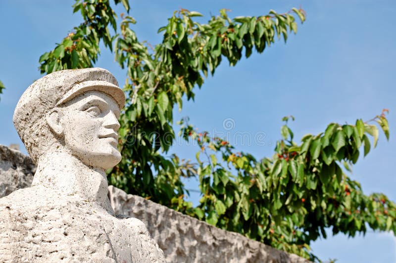 Russian communism socialistic ideology statue in the park of the statue near Budapest, Hungary. Cherry tree on background. Russian communism socialistic ideology statue in the park of the statue near Budapest, Hungary. Cherry tree on background.