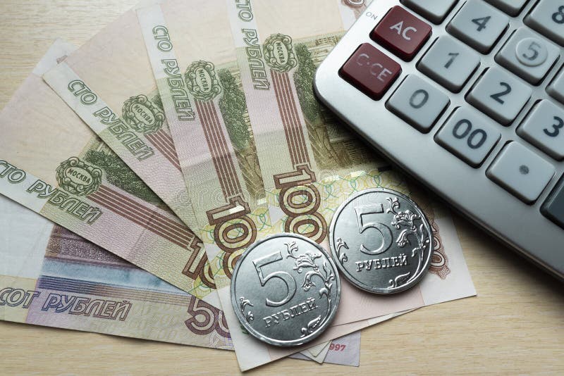 Russian money spread out in a fan and a calculator with a close-up on a light background. Russian money spread out in a fan and a calculator with a close-up on a light background.