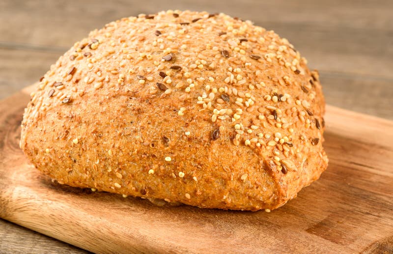 Rustic bread with sesame and flax seeds on the wooden cutter