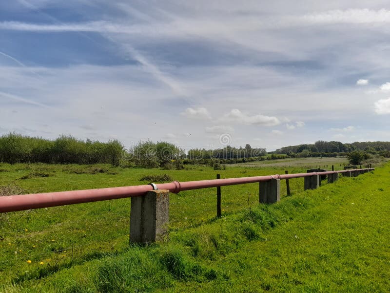 Rustic Countryside with Elevated Pipeline and Lush Green Field royaltyfria bilder