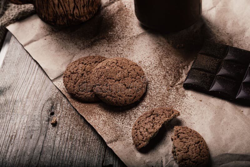 Rustic, dark and blurry background. grain. On the table is a jar of chocolate nut paste, a mug and oatmeal cookies stock photo