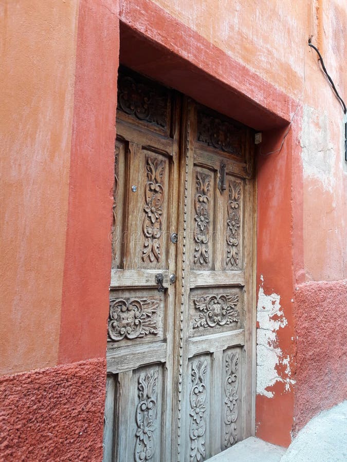 Rustic Hand-Carved Antique Wooden Door and Primitive Textured Mexican Stucco Wall in Brown, Rust and Tan Background Colors stock photos Rustic Hand-Carved Antique Wooden Door and Primitive Textured Mexican Stucco Wall in Brown, Rust and Tan Background Colors stock photos