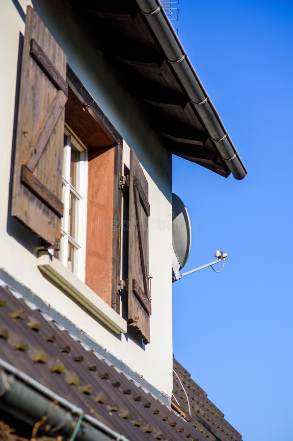 Rustic house with wooden shutters and satellite antenna