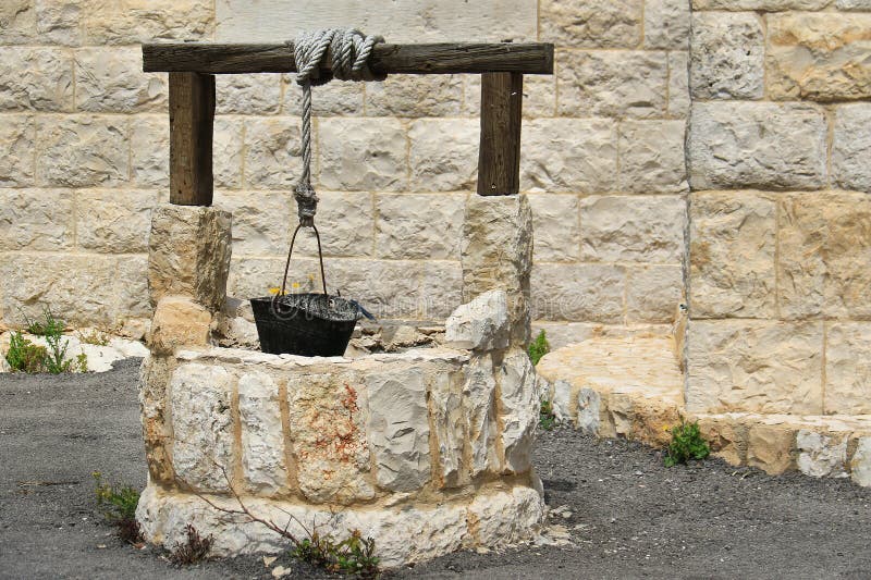 A rustic well made of stone with a metallic bucket in a Lebanese village