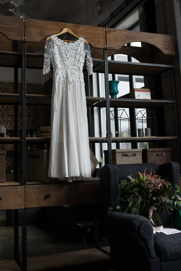 Rustic White Wedding Dress Hanging on the Cupboard. Loft Interior Stock