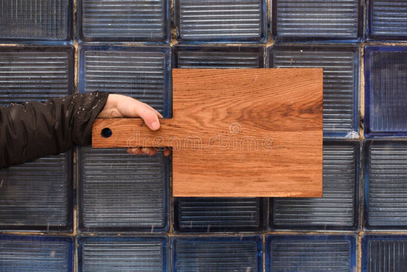 Rustic Wood Cutting Board Held in Hand on Glass Bricks Textured Stock