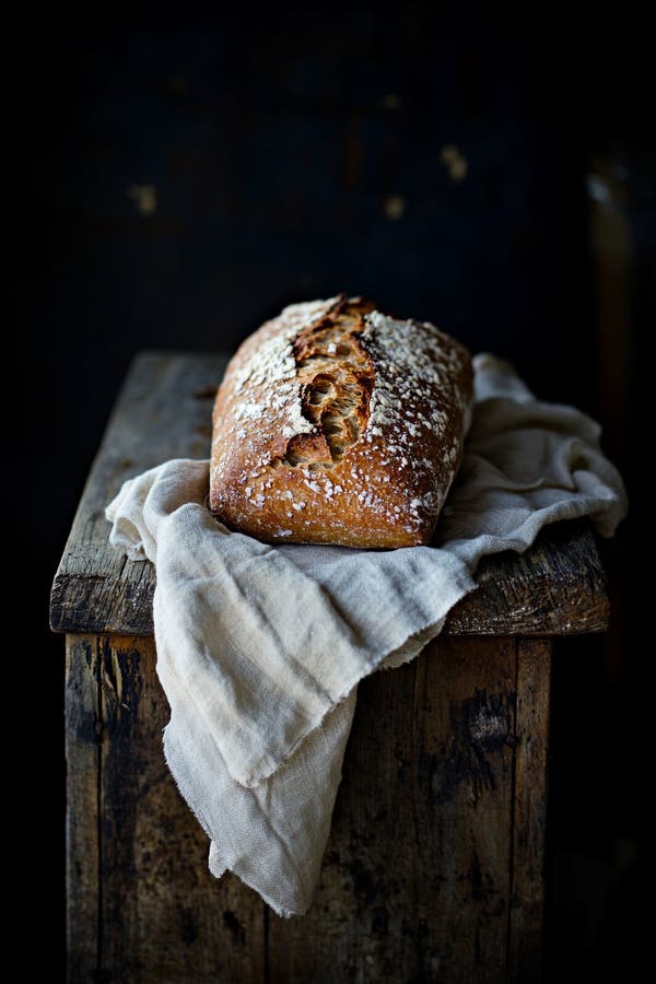 Rustikales hausgemachtes Brot mit goldener Kruste und Salzkörner auf einem Holzbrett stock abbildung