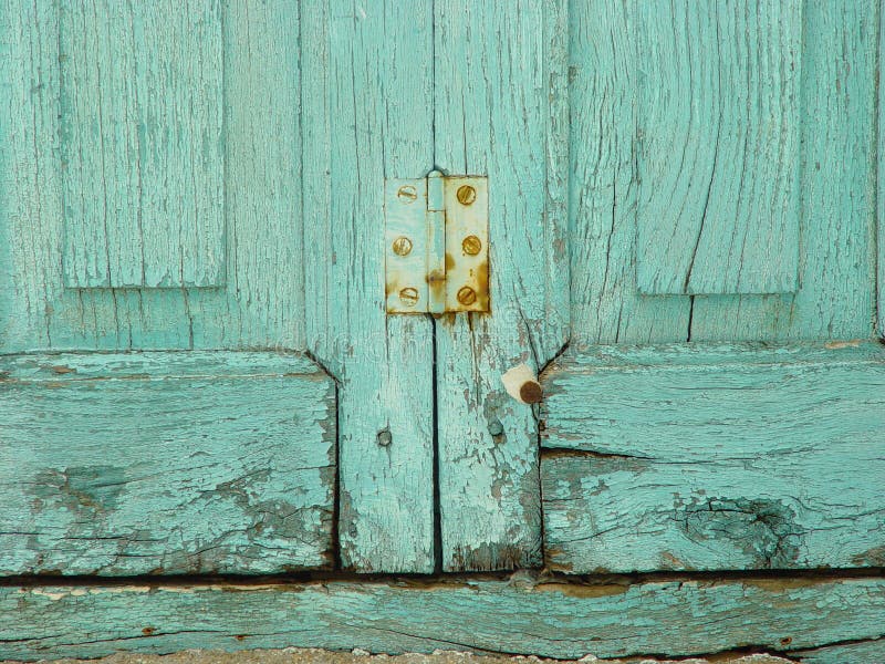 Rusty hinge on worn turquoise window shutters