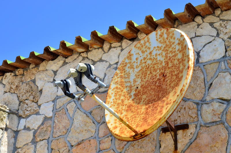 Rusty satellite TV radio internet wifi antenna on the wall of ancient house.