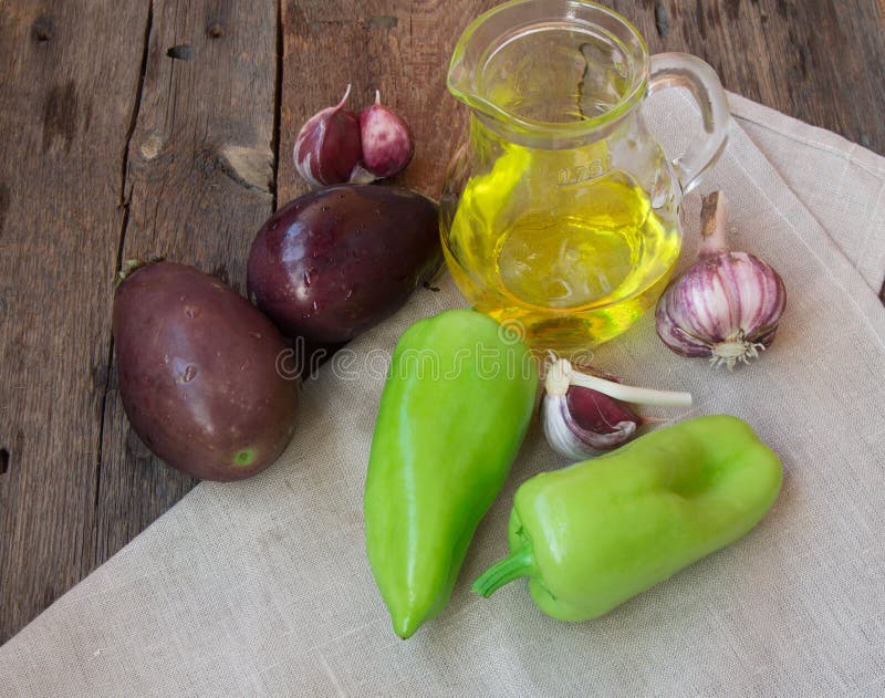 Ruwe aubergine, knoflook, olijfolie, paprika, het gezond eten en dieetconcept op de oude houten achtergrond stock afbeeldingen Ruwe aubergine, knoflook, olijfolie, paprika, het gezond eten en dieetconcept op de oude houten achtergrond stock afbeeldingen
