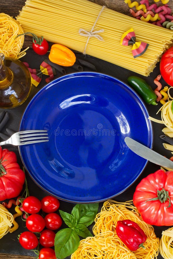 Ruwe deegwaren met ingridients en blauwe plaat stock afbeelding Ruwe deegwaren met ingridients en blauwe plaat stock afbeelding