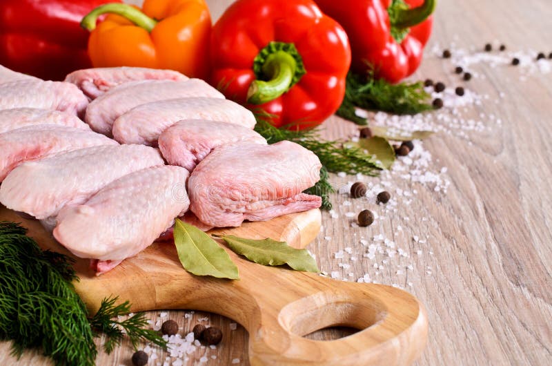 Raw chicken wings on a wooden Board on the background of paprika and spices. Raw chicken wings on a wooden Board on the background of paprika and spices